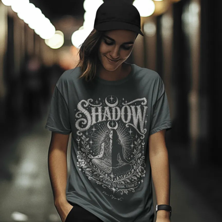 Woman wearing Shadow T-Shirt walking outdoors at night wearing a cap, shirt in Dark Heather Grey.