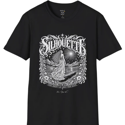 A short sleeved tee called the Silhouette T-Shirt, flat lay and a Gildan 64000 shirt on a white background. Simply says, Light Doesn't Lie About Your Shape. Design highlights a long-haired figure in a flowing gown gazing at a radiating star, framed by ornate florals, mountains and a lake, with the figure's cast shadow on the path. Color is Black.