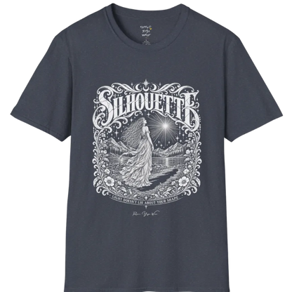 A short sleeved tee called the Silhouette T-Shirt, flat lay and a Gildan 64000 shirt on a white background. Simply says, Light Doesn't Lie About Your Shape. Design highlights a long-haired figure in a flowing gown gazing at a radiating star, framed by ornate florals, mountains and a lake, with the figure's cast shadow on the path. Color is Heather Navy.