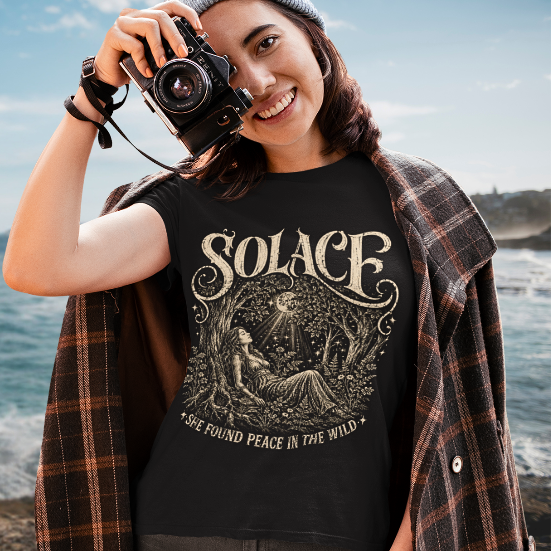 Person wearing Solace T-Shirt in black sacred yoga shirt at the lake, holding a vintage camera — Wild Devotion collection by Ramro Yoga Wear