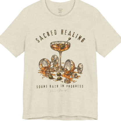 A grunge tee with an illustrated design of three cocktail glasses — one upright, two spilled with ice cubes and olives scattered — text reading "Sacred Healing" and "Sound Bath In Progress" — Funny Yoga Shirts collection by Ramro Yoga Wear in Heather Natural Prism.