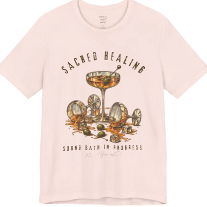 A grunge tee with an illustrated design of three cocktail glasses — one upright, two spilled with ice cubes and olives scattered — text reading "Sacred Healing" and "Sound Bath In Progress" — Funny Yoga Shirts collection by Ramro Yoga Wear in Soft Pink