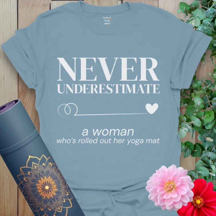 Stone Blue Never Underestimate T-Shirt featuring premium serif text and gentle script. Empowering yoga quote with swirl and heart icon.