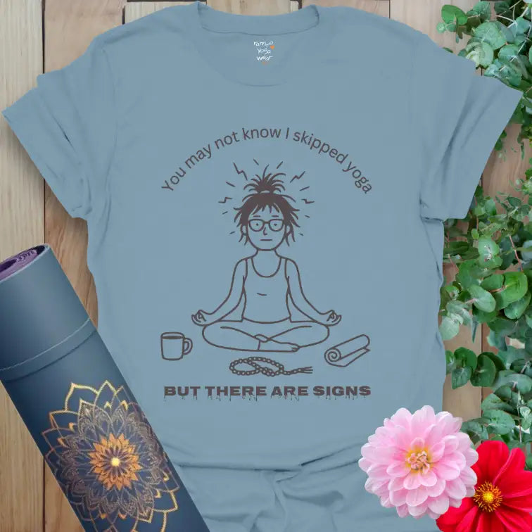 Stone Blue Signs T-Shirt featuring relaxed yogi line-art illustration. “Skipped yoga but there are signs” design for mindful humor and calm vibes.