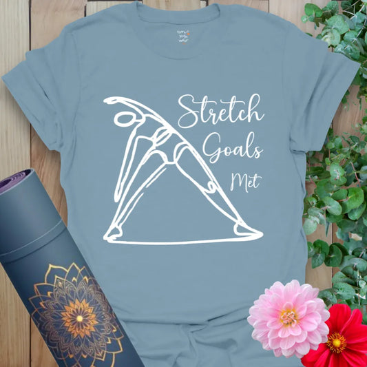 Muted stone blue yoga tee with elegant stretch illustration and “Stretch Goals Met” text, made for yogis with humor and heart.