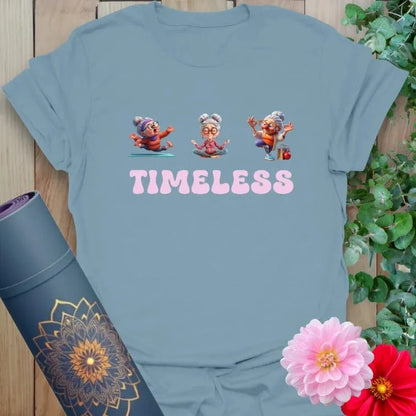 Muted stone blue t-shirt with animated elder yogi/dancer design and “TIMELESS” script for graceful, ageless living.
