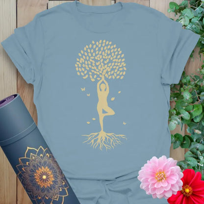 Muted stone blue yoga t-shirt with golden yogi in Tree Pose and leafy, rooted accents for grounded spiritual style.