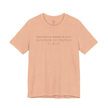 PROFESSIONAL HOLDER OF SPACE IGNORER OF PHONES yoga teacher gift tee flat lay in Heather Peach — Yoga Teacher Gifts collection by Ramro Yoga Wear
