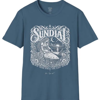 A short sleeved tee called the Sundial T-Shirt, flat lay and a Gildan 64000 shirt. Simply says, Read What You Cast. Design highlights a woman reading a sundial beneath a starry sky, with mountains and a rising sun in the background, in a detailed vintage-inspired illustration. Color is Indigo Blue.