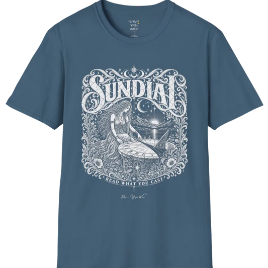 A short sleeved tee called the Sundial T-Shirt, flat lay and a Gildan 64000 shirt. Simply says, Read What You Cast. Design highlights a woman reading a sundial beneath a starry sky, with mountains and a rising sun in the background, in a detailed vintage-inspired illustration. Color is Indigo Blue.