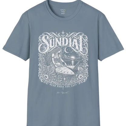 A short sleeved tee called the Sundial T-Shirt, flat lay and a Gildan 64000 shirt. Simply says, Read What You Cast. Design highlights a woman reading a sundial beneath a starry sky, with mountains and a rising sun in the background, in a detailed vintage-inspired illustration. Color is Stone Blue.
