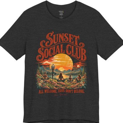 A short sleeved tee called the Sunset T-Shirt, flat lay and a Bella + Canvas 3001 shirt. Simply says, Sunset Social Club, All Welcome, Egos Don't Belong. Design highlights several people meditating together across a mountain landscape at sunset, with a large setting sun, pine trees, and florals, in a color vintage travel-poster illustration. Color is Dark Grey Heather.