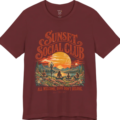 A short sleeved tee called the Sunset T-Shirt, flat lay and a Bella + Canvas 3001 shirt. Simply says, Sunset Social Club, All Welcome, Egos Don't Belong. Design highlights several people meditating together across a mountain landscape at sunset, with a large setting sun, pine trees, and florals, in a color vintage travel-poster illustration. Color is Heather Cardinal.