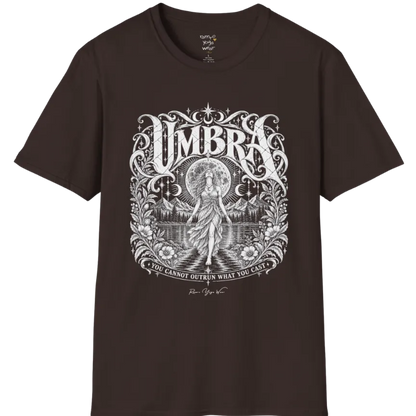 A short sleeved tee called the Umbra T-Shirt, flat lay and a Gildan 64000 shirt. Simply says, You Cannot Outrun What You Cast. Design highlights a moon goddess walking across still water toward distant mountains, framed in ornate vintage lettering with botanical detailing. Color is Dark Chocolate.