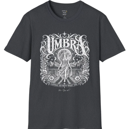A short sleeved tee called the Umbra T-Shirt, flat lay and a Gildan 64000 shirt. Simply says, You Cannot Outrun What You Cast. Design highlights a moon goddess walking across still water toward distant mountains, framed in ornate vintage lettering with botanical detailing. Color is Dark Heather Grey.