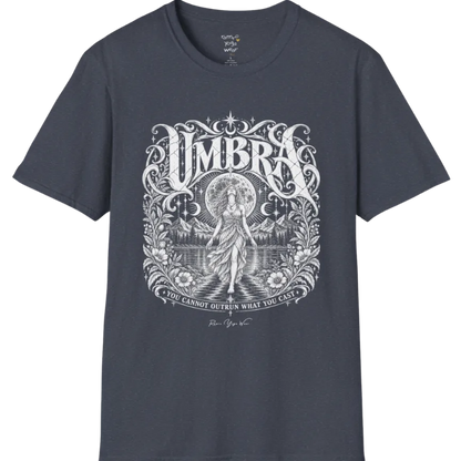 A short sleeved tee called the Umbra T-Shirt, flat lay and a Gildan 64000 shirt. Simply says, You Cannot Outrun What You Cast. Design highlights a moon goddess walking across still water toward distant mountains, framed in ornate vintage lettering with botanical detailing. Color is Heather Navy.