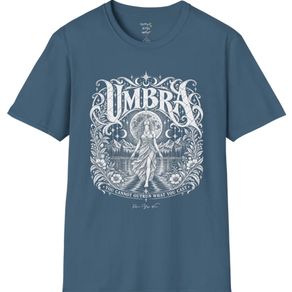 A short sleeved tee called the Umbra T-Shirt, flat lay and a Gildan 64000 shirt. Simply says, You Cannot Outrun What You Cast. Design highlights a moon goddess walking across still water toward distant mountains, framed in ornate vintage lettering with botanical detailing. Color is Indigo Blue.