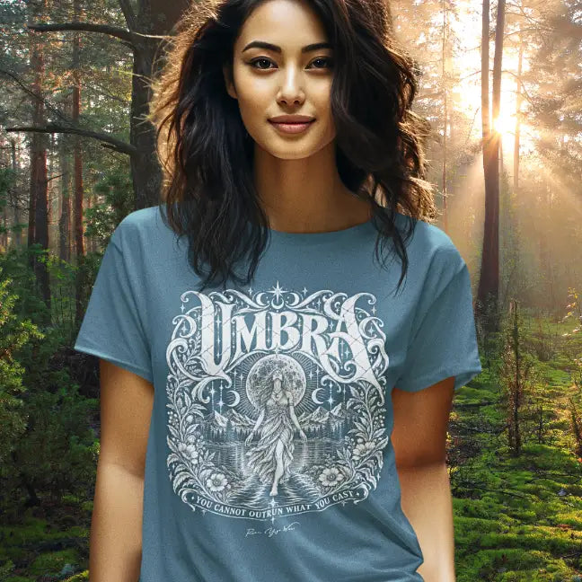 Woman wearing Umbra T-Shirt outdoors in a sunlit forest, color Indigo Blue.