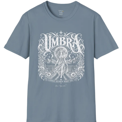 A short sleeved tee called the Umbra T-Shirt, flat lay and a Gildan 64000 shirt. Simply says, You Cannot Outrun What You Cast. Design highlights a moon goddess walking across still water toward distant mountains, framed in ornate vintage lettering with botanical detailing. Color is Stone Blue.