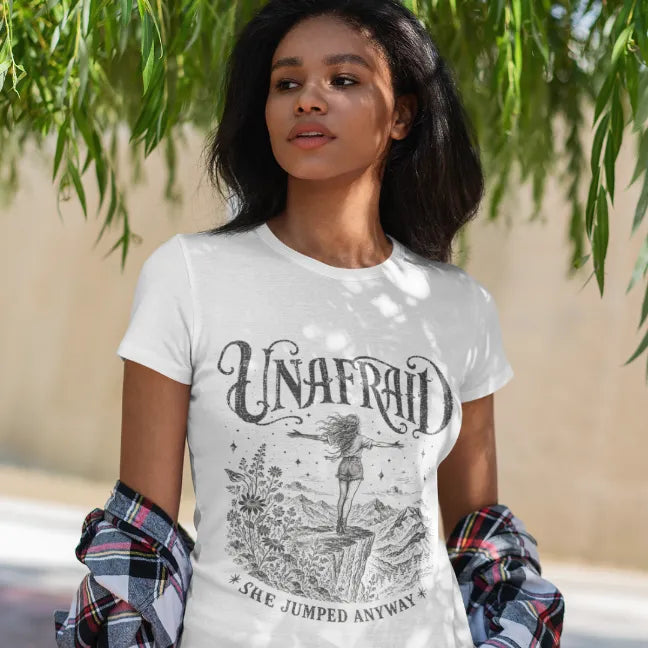 Woman wearing the White Unafraid T-Shirt in a natural outdoor setting featuring celestial Western-inspired artwork and soulful feminine energy.