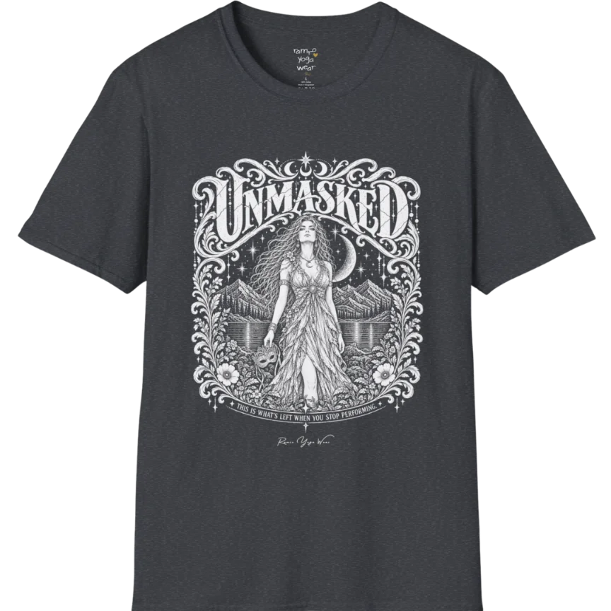 A short sleeved tee called the Unmasked T-Shirt, flat lay and a soft cotton shirt. Simply says, Unmasked. Design highlights an ornate floral crest in white linework with a long-haired figure in a flowing gown beneath a crescent moon, with Unmasked in ornate lettering across the top. Color is Dark Heather Grey.