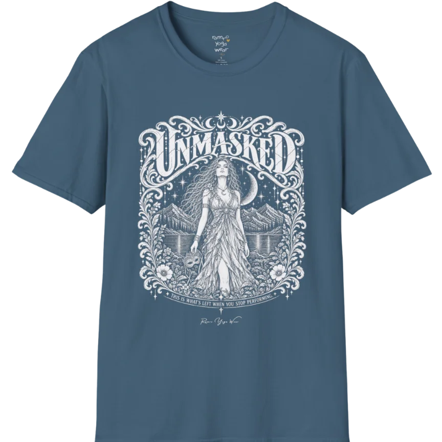 A short sleeved tee called the Unmasked T-Shirt, flat lay and a soft cotton shirt. Simply says, Unmasked. Design highlights an ornate floral crest in white linework with a long-haired figure in a flowing gown beneath a crescent moon, with Unmasked in ornate lettering across the top. Color is Indigo Blue.