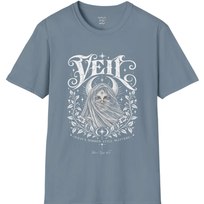 A short sleeved Tee, illustrated with a face partially obscured behind sheer draped fabric, a crescent moon behind, fine botanical framing at the base. Veil T-Shirt flat lay is a Gildan 64000 and the color is Stone Blue.