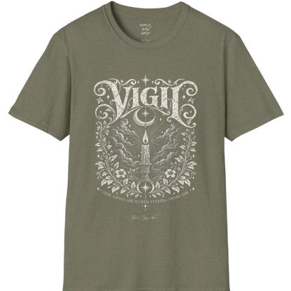 Short sleeved tee, illustration of a single candle burning steady against stormy clouds and wind lines, flame untouched, fine botanical framing at the base. Vigil T-Shirt flat lay is a Gildan 64000 and the color is Heather Military Green.