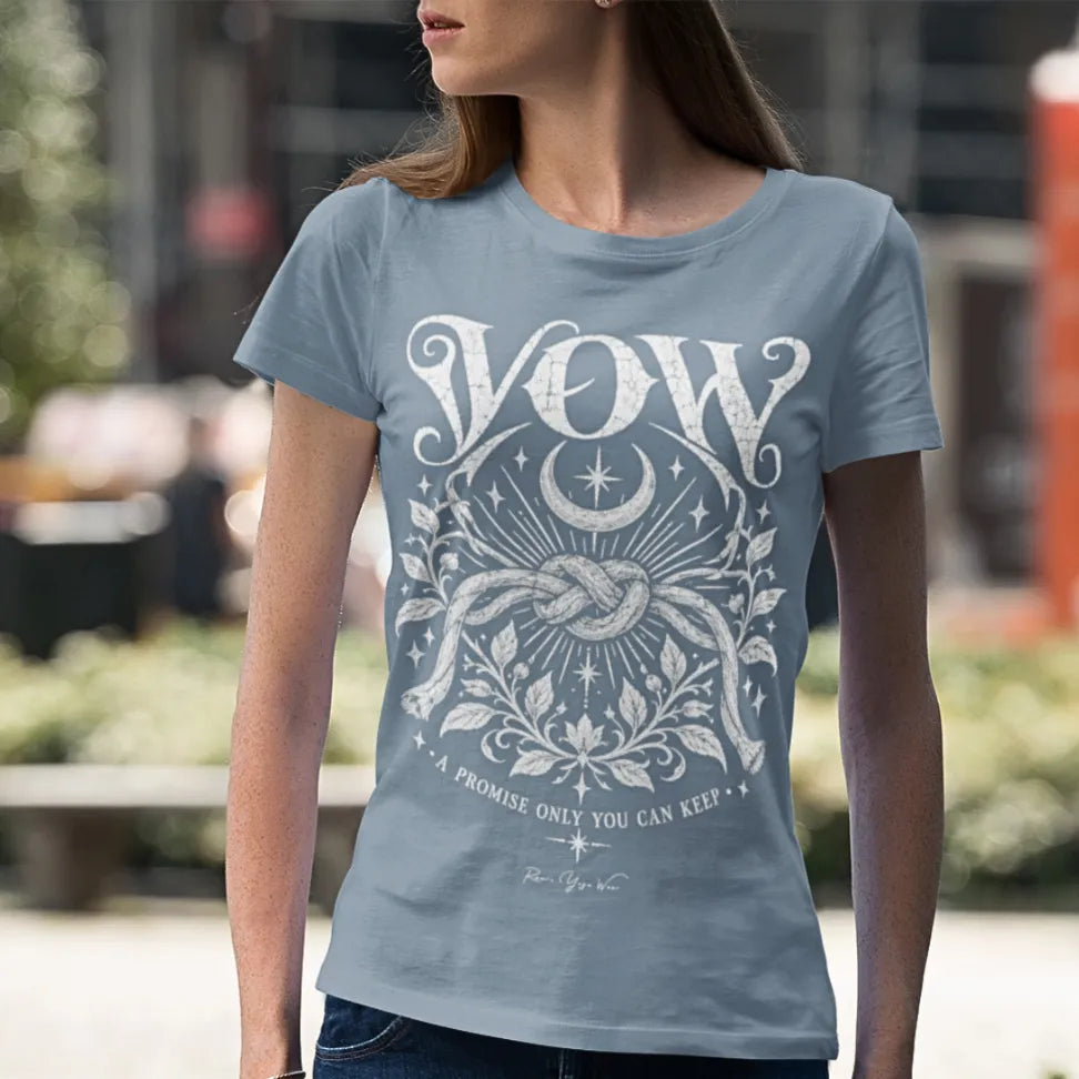A woman stands on an urban street, wearing the Vow T-Shirt. Vow T-Shirt is a Gildan 64000 short sleeved tee and the color is Stone Blue.