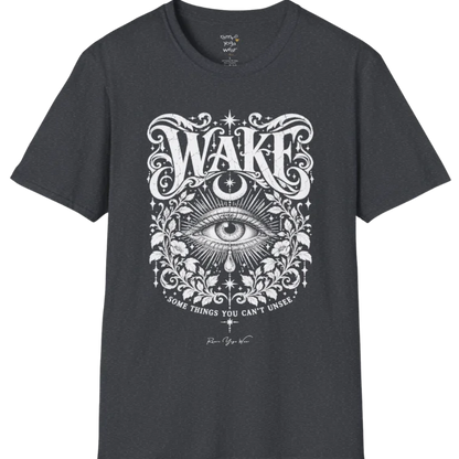 A short sleeved tee with an illustration of a single open eye amid darkness with a dewdrop caught mid-fall beneath it, faint stars scattered around, fine botanical framing at the base. Wake T-Shirt flat lay is a Gildan 64000 and the color is Dark Heather Grey.