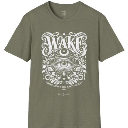 A short sleeved tee with an illustration of a single open eye amid darkness with a dewdrop caught mid-fall beneath it, faint stars scattered around, fine botanical framing at the base. Wake T-Shirt flat lay is a Gildan 64000 and the color is Heather Military Green.