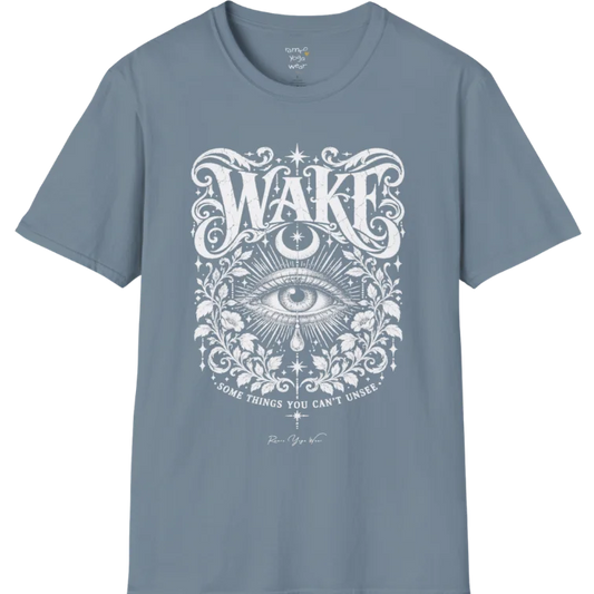 A short sleeved tee with an illustration of a single open eye amid darkness with a dewdrop caught mid-fall beneath it, faint stars scattered around, fine botanical framing at the base. Wake T-Shirt flat lay is a Gildan 64000 and the color is Stone Blue.