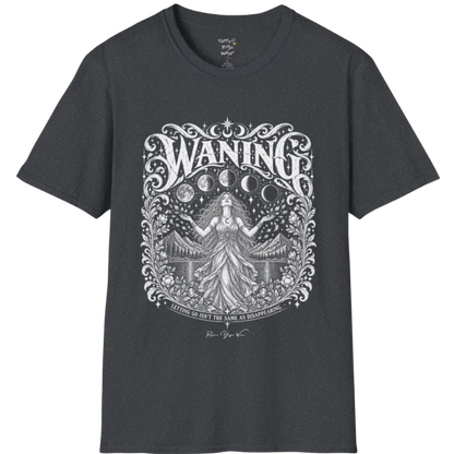 A short sleeved tee called the Waning T-Shirt, flat lay and a Gildan 64000 shirt. Simply says, Waning, Letting Go Isn't The Same As Disappearing. Design highlights a vintage-engraved crest of a robed figure with long flowing hair and open hands releasing petals beneath five moon phases, with mountains, a still lake, stars and ornate floral framing. Color is Dark Heather Grey.