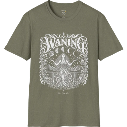 A short sleeved tee called the Waning T-Shirt, flat lay and a Gildan 64000 shirt. Simply says, Waning, Letting Go Isn't The Same As Disappearing. Design highlights a vintage-engraved crest of a robed figure with long flowing hair and open hands releasing petals beneath five moon phases, with mountains, a still lake, stars and ornate floral framing. Color is Heather Military Green.