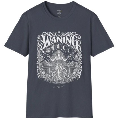 A short sleeved tee called the Waning T-Shirt, flat lay and a Gildan 64000 shirt. Simply says, Waning, Letting Go Isn't The Same As Disappearing. Design highlights a vintage-engraved crest of a robed figure with long flowing hair and open hands releasing petals beneath five moon phases, with mountains, a still lake, stars and ornate floral framing. Color is Heather Navy.