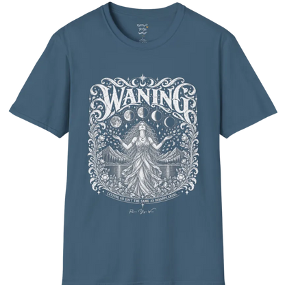 A short sleeved tee called the Waning T-Shirt, flat lay and a Gildan 64000 shirt. Simply says, Waning, Letting Go Isn't The Same As Disappearing. Design highlights a vintage-engraved crest of a robed figure with long flowing hair and open hands releasing petals beneath five moon phases, with mountains, a still lake, stars and ornate floral framing. Color is Indigo Blue.
