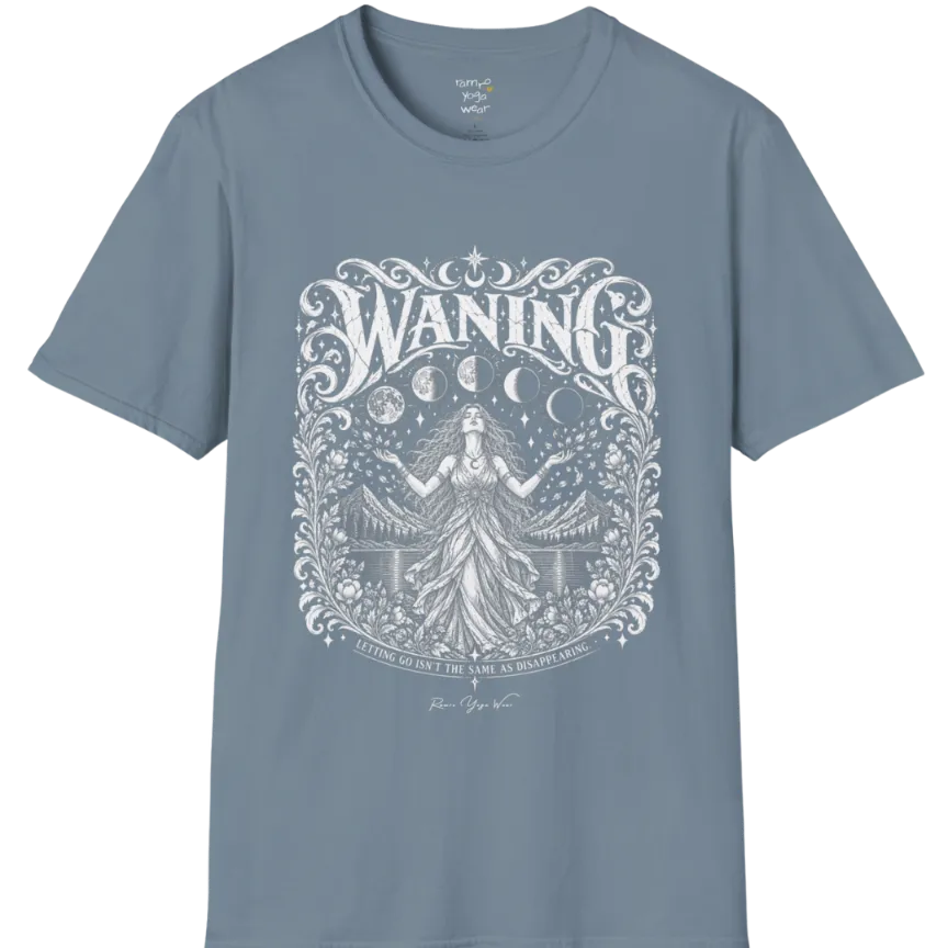 A short sleeved tee called the Waning T-Shirt, flat lay and a Gildan 64000 shirt. Simply says, Waning, Letting Go Isn't The Same As Disappearing. Design highlights a vintage-engraved crest of a robed figure with long flowing hair and open hands releasing petals beneath five moon phases, with mountains, a still lake, stars and ornate floral framing. Color is Stone Blue.