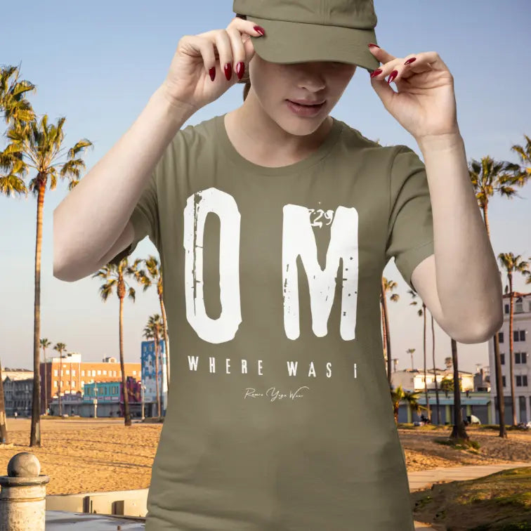 Person wearing Where Was I Heather Olive color sacred yoga shirt adjusting a cap at the beach with palm trees — Funny Yoga Shirts collection by Ramro Yoga Wear