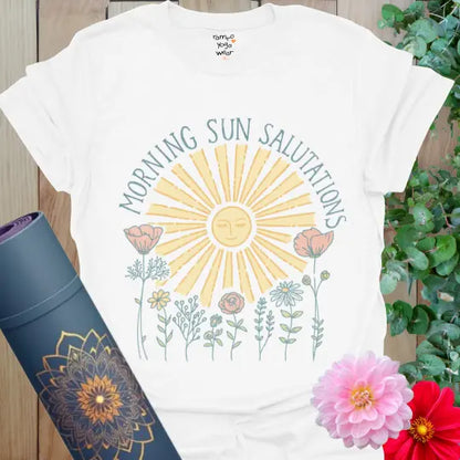 White Morning Sun Salutations T-Shirt with pastel yellow sun, soft floral line art, and arch text. Radiant yoga tee for mindful mornings.