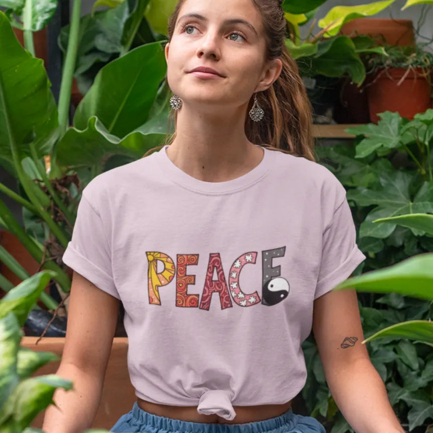 Woman wearing Yin Yang Peace T-Shirt Light Pink sacred yoga shirt outdoors in a garden setting — The Vault collection by Ramro Yoga Wear
